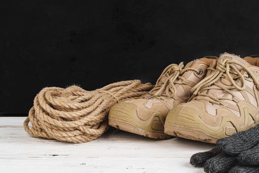 Hiking boots and rope hank on wooden board close up