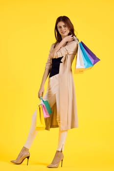 cheerful woman with multicolored bags posing yellow background. High quality photo