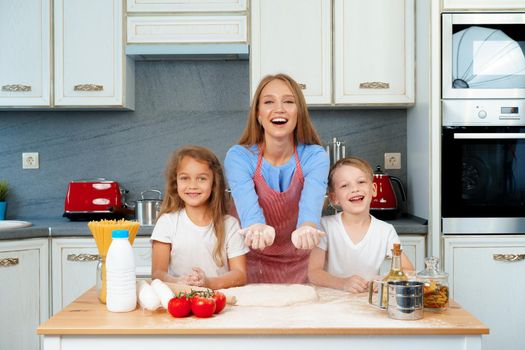 Young blonde woman, mother and her kids having fun while cooking dough close up
