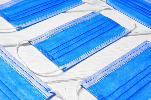 Blue medical face masks on white wooden background