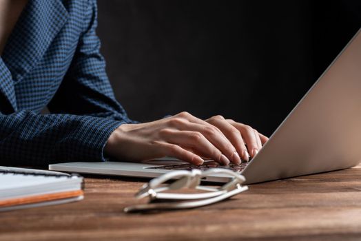 Close up woman hands lying on laptop keyboard. Business lady working with computer at wooden desk. Financial specialist working at workplace in office. Human resources and career development.