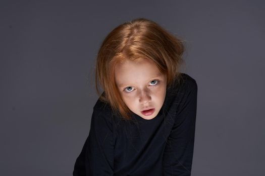 red-haired girl with freckles on her face in a black sweater posing. High quality photo