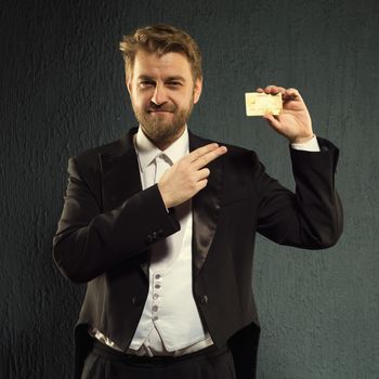 Positive man in a tailcoat pointing finger to the credit card. - image