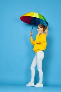 woman with multicolored umbrella in yellow sweater posing rainbow colors. High quality photo