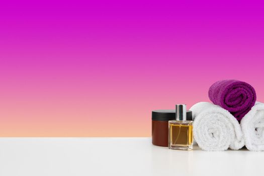Pile of towels, bottles with shampoo on white table isolated