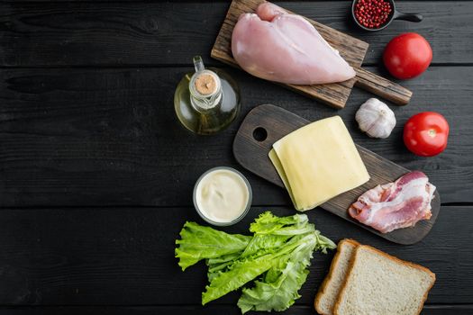 Ingredients for sandwich, bacon, cheese, tomato, chicken meat, lettuce, sauce, on black wooden table, top view with copy space for text