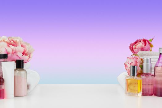 Stack of white towels and bottles of skincare on white table, front view