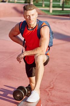 athletic man with dumbbells in his hands outdoors in the park. High quality photo