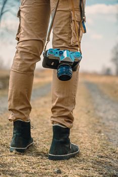 Unrecognizable traveler with vintage photo camera on a road