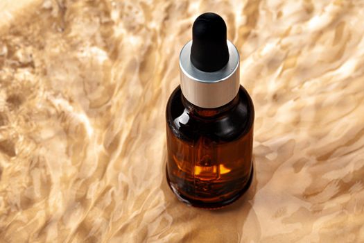 Oil cosmetic bottle on water waves background, top view