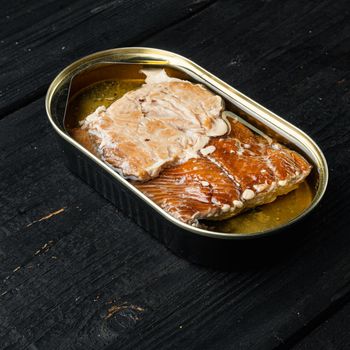 Wild Alaska Salmon Canned smoked fish set, in tin can, on black wooden table background, with copyspace and space for text, square format
