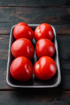 Red tomatoes, on dark wooden background