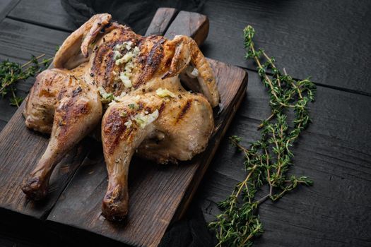 Roasted spatchcock poussin meal, on black wooden table