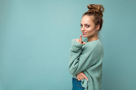 Portrait of young beautiful smiling hipster woman in trendy outfit. Sexy carefree female person posing isolated near blue wall in studio with free space. Positive model with natural makeup.