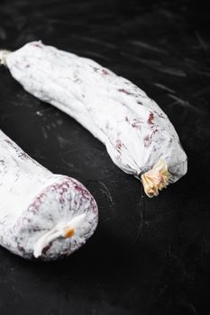 Traditional spanish sausages fuet and chorizo on black textured background.