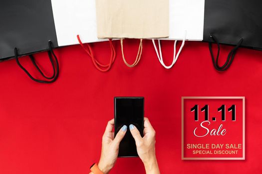 China 11.11 single day sale concept, woman hand holding smartphone with shopping bag.