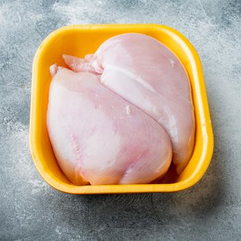 Raw chicken breast fillets in tray, on gray background