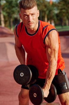 Muscled Man With Dumbbells Outdoor Workout. High quality photo