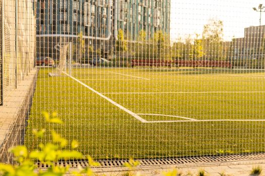 Soccer or football net background, view from behind the goal with blurred stadium and field pitch.