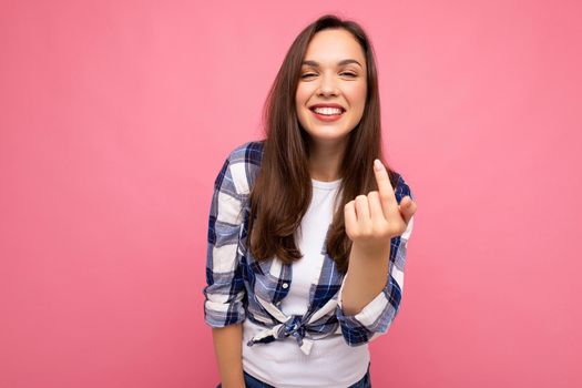 Shot of young happy smiling beautiful brunette lady with sincere emotions wearing trendy check shirt isolated on pink background with empty space.