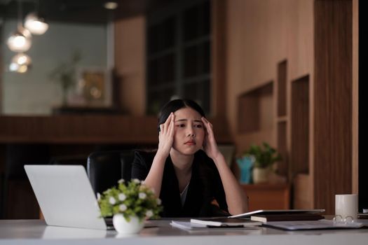 Stressed business woman working on laptop looking worried, tired and overwhelmed. asian female headache suffer from bad blurry weak vision tired of computer work syndrome, sight problem concept.