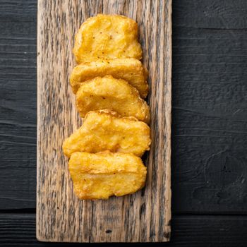 Homemade chicken nuggets fried on black wooden background, flat lay, with space for text.