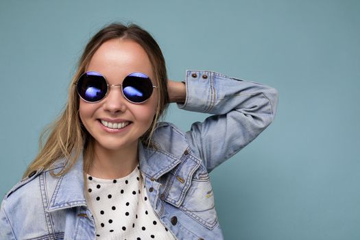 Closeup portrait photo shot of beautiful positive young blonde woman wearing summer casual clothes and stylish sunglasses isolated over colorful background looking at camera.