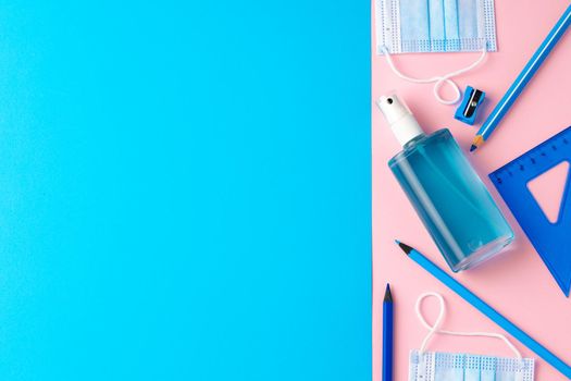 Hand sanitizer gel and school supplies top view, copy space
