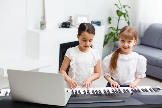 Home lesson on music for the girl on the piano. The idea of activities for the child at home during quarantine. Music concept