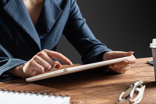 Businesswoman using tablet computer at desk. Close up woman hand pointing on touchscreen. Online stock trading and financial analytics. Digital technology in strategy planning and company management