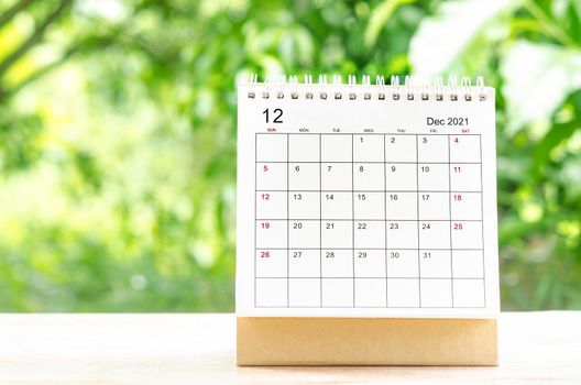 December 2021 Calendar desk for organizer to plan and reminder on wooden table on nature background.