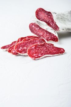 Sliced cuts of longaniza, dry cured spanish sausage on white textured background with space for text.