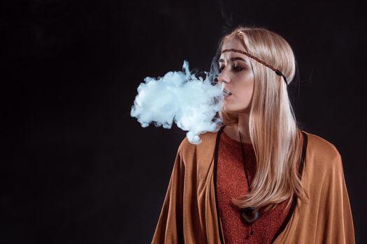 Girl in the Boho style blowing smoke. The blonde on a dark background
