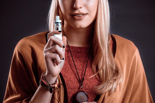 Young woman in the Boho style blowing smoke. The blonde on a dark background. Close-up