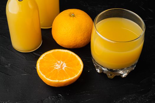 Glass jar of fresh Tangerine juice set, on black dark stone table background
