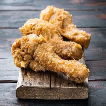 Crispy fried chicken drumstick on old dark wooden table.