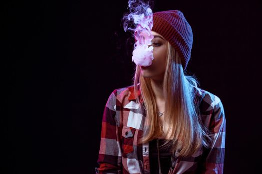 young woman smoking electronic cigarette on black background