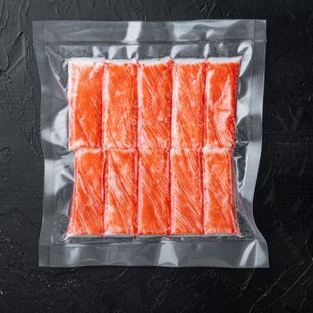Crab sticks in vacuum pack set, on black background, top view flat lay
