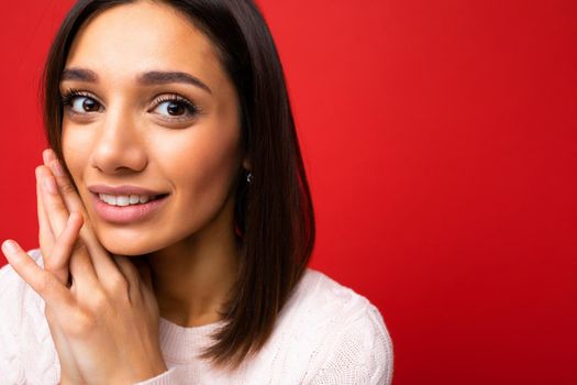 Closeup portrait of positive cheerful cute smiling young brunette woman in casual sweater isolated on red background with copy space.