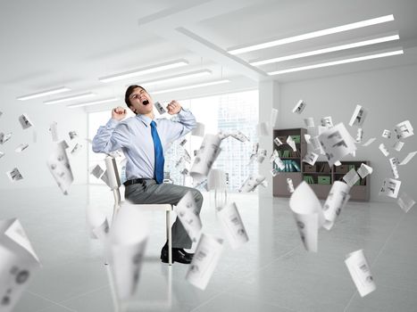 young businessman yawns and stretches while sitting on a chair