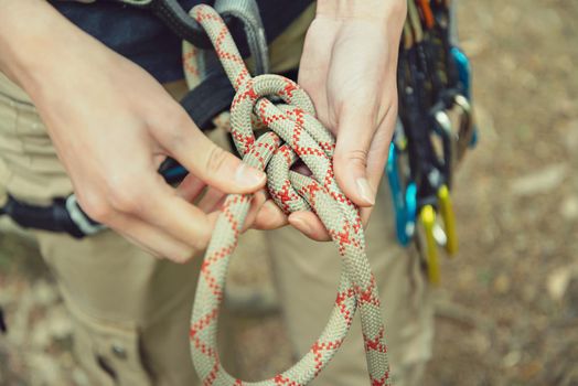 Climber woman doing a figure eight knot outdoor, view of hands, close-up