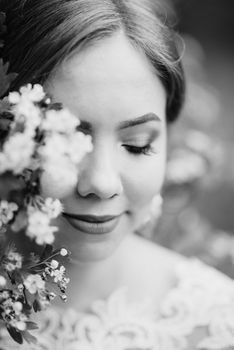 bride with a wedding bouquet in the forest near the bushes blooming with white flowers