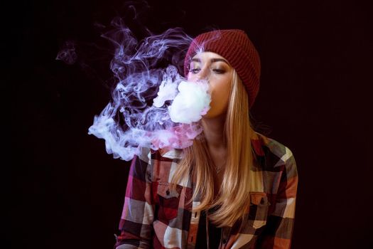 young woman smoking electronic cigarette on black background