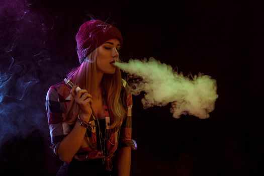 young woman smoking electronic cigarette on black background