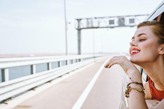 cheerful woman peeking out of the car window trip road travel. High quality photo