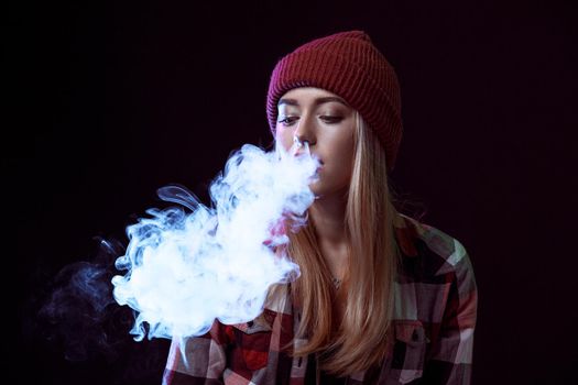 young woman smoking electronic cigarette on black background