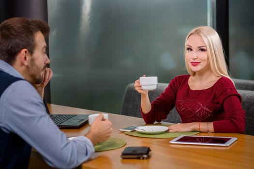 A woman and a man on a business lunch in a restaurant, drink coffee