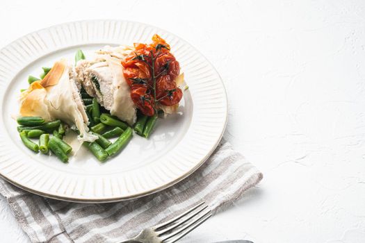 Stuffed chicken meat with filo set, with baked cherry tomatoes And green beans, on white stone background, with copy space for text