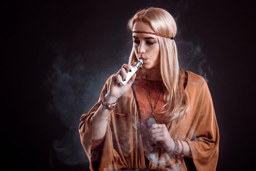 Young woman in the Boho style blowing smoke. The blonde on a dark background