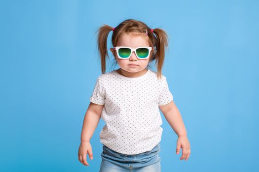 Fashion portrait of girl child on a blue background. Sunglasses.